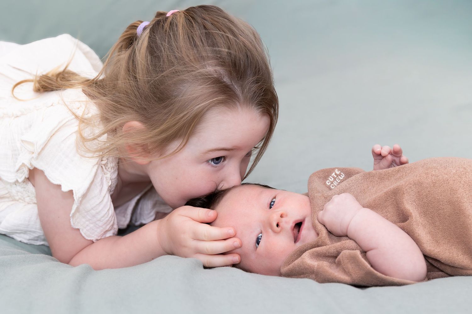 A series of tender parent and child moments showing gentle kisses and cuddles on a light background.