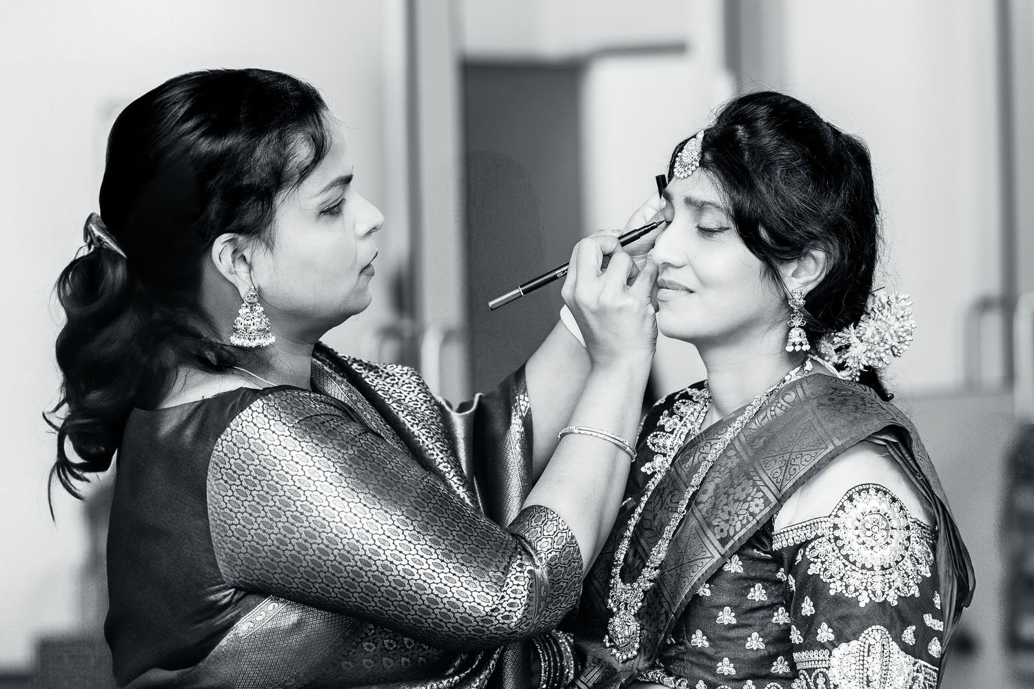 A black and white photo series showing makeup application and final glamorous look for a special occasion.