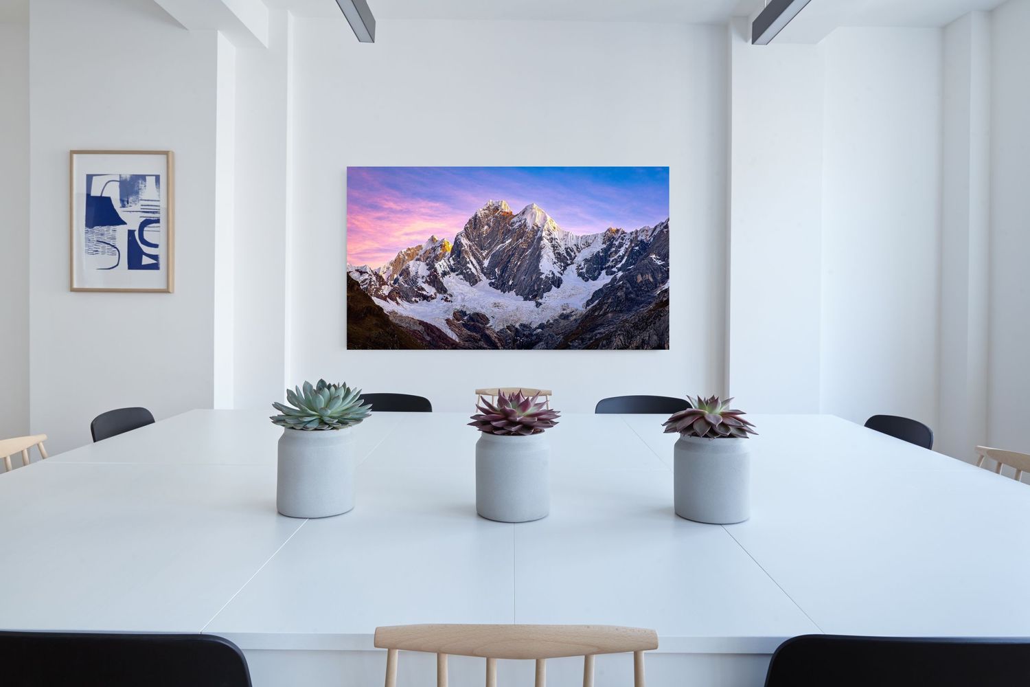 A fine art print of Cordillera Huayhuash hanging on the wall in a conference room