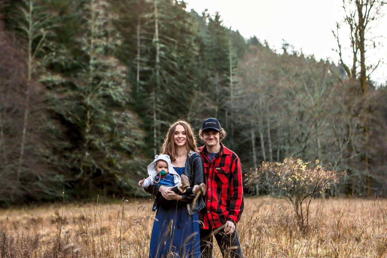 Family enjoying an autumn day together in a forest clearing with evergreen trees.