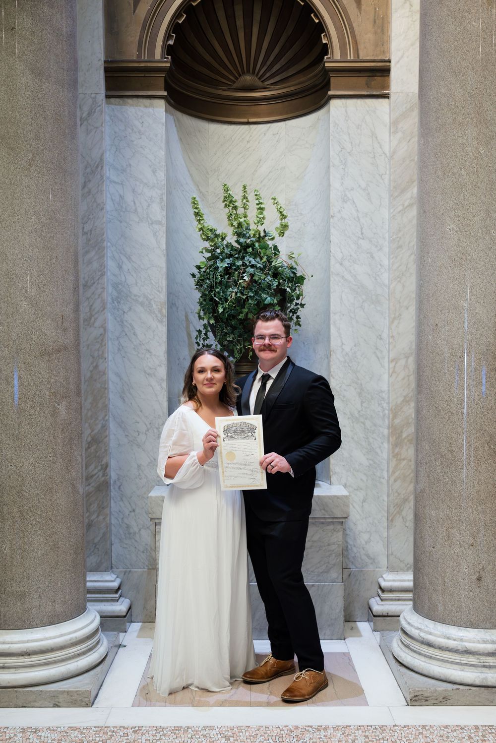 Wedding photos taken against classical stone columns and architecture.