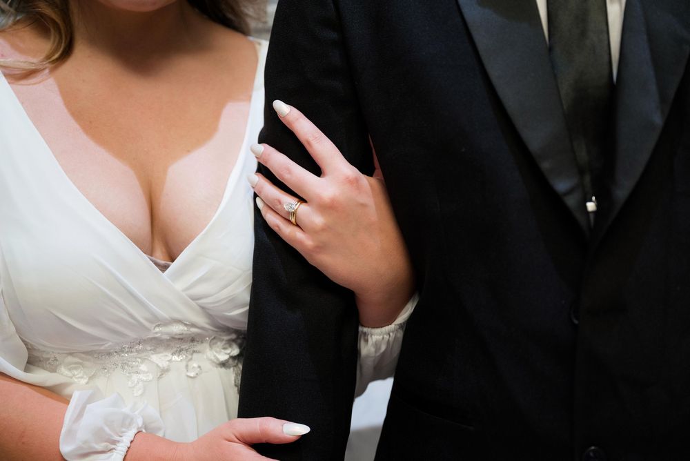 Tender moment captured during wedding ceremony with bride in white dress and groom in formal attire.