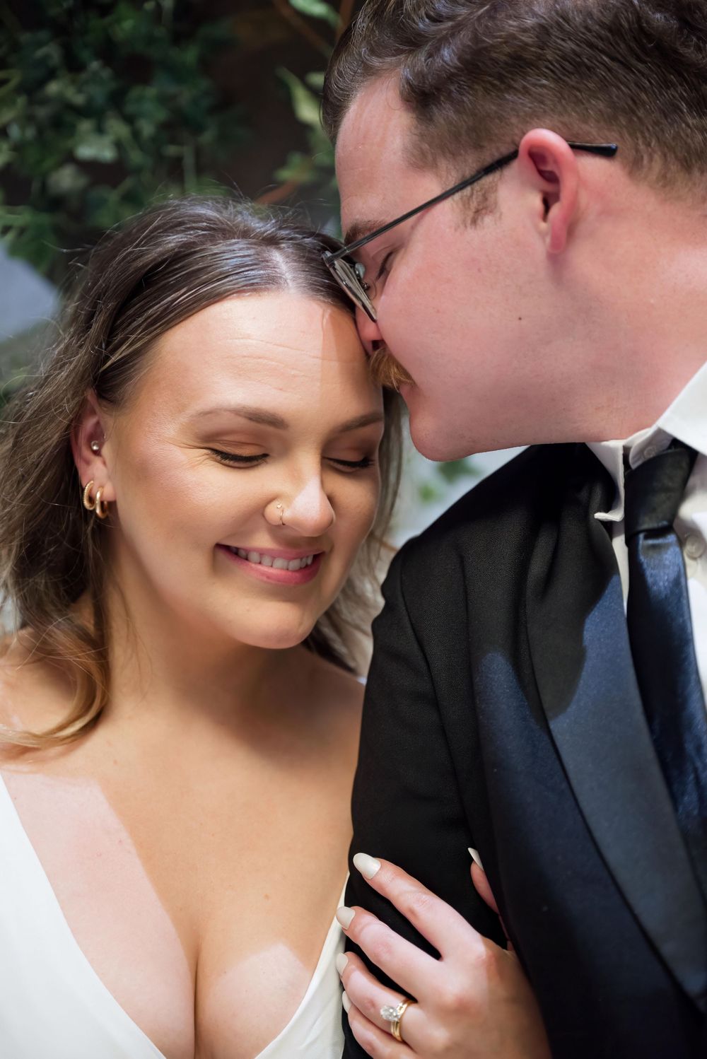 A tender moment between a couple in formal attire against a natural backdrop.