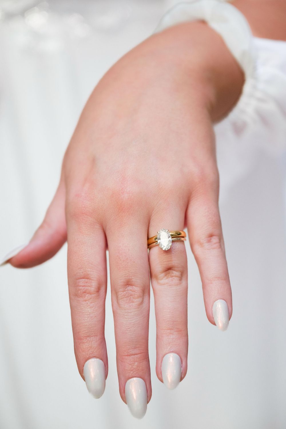Close-up shots of a bride's hand showing an elegant engagement ring with white nail polish.