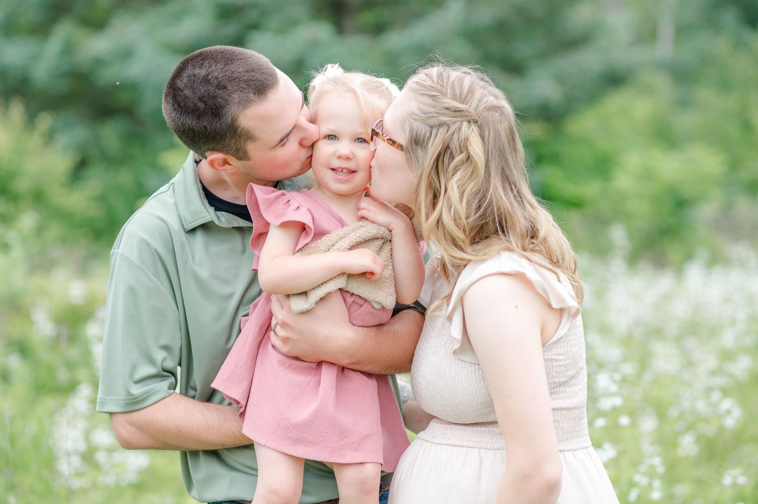 Normal, Illinois parents kissing their daughter on the cheeks during a family photography session by Julie Loy Photography