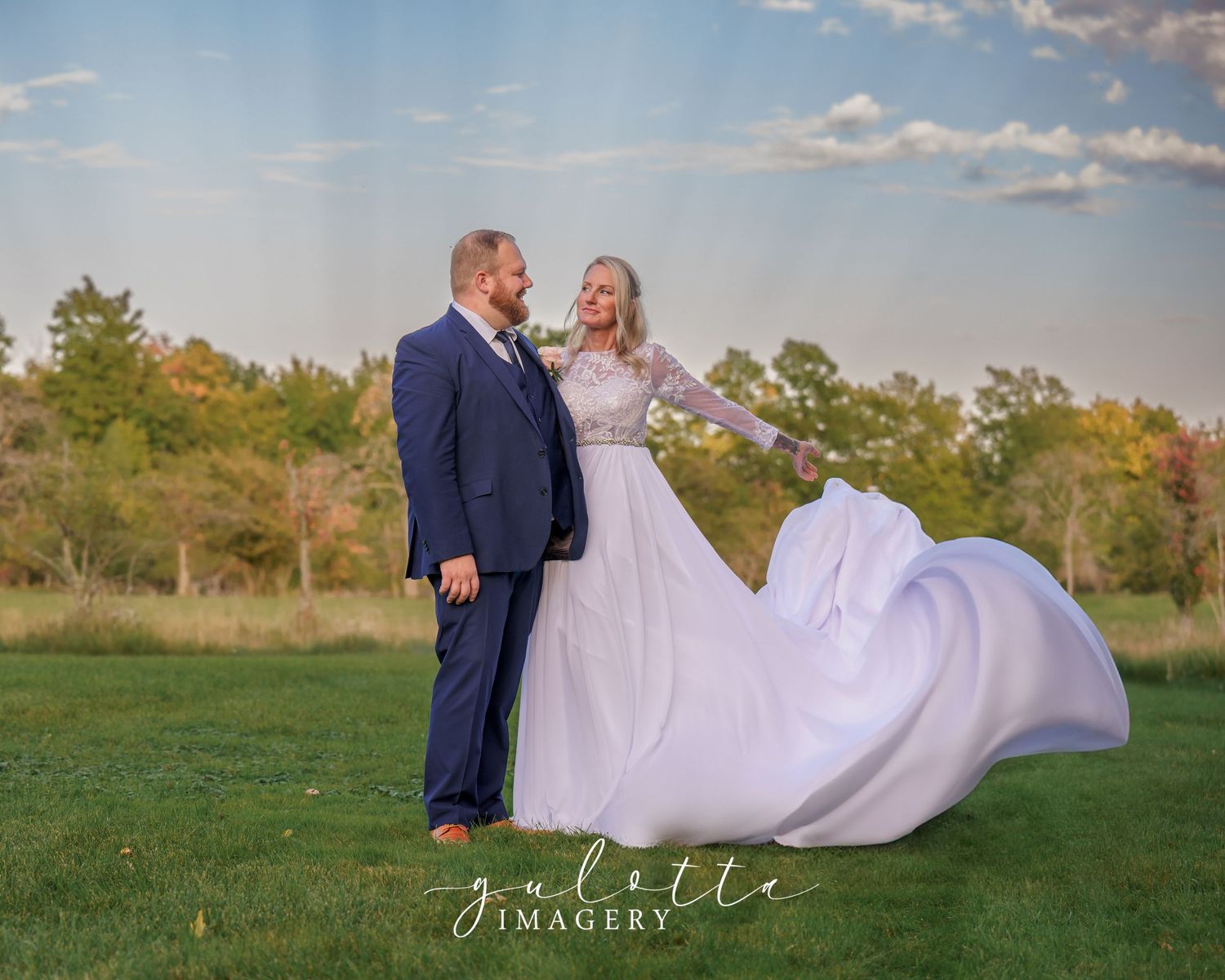 Close up view of a newlywed couple in traditional white wedding attire sharing an intimate moment under a veil.
