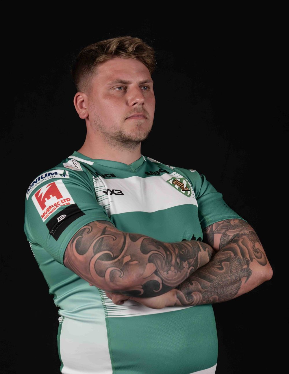 Athletic apparel shots showing green and white jersey with detailed arm tattoos.
