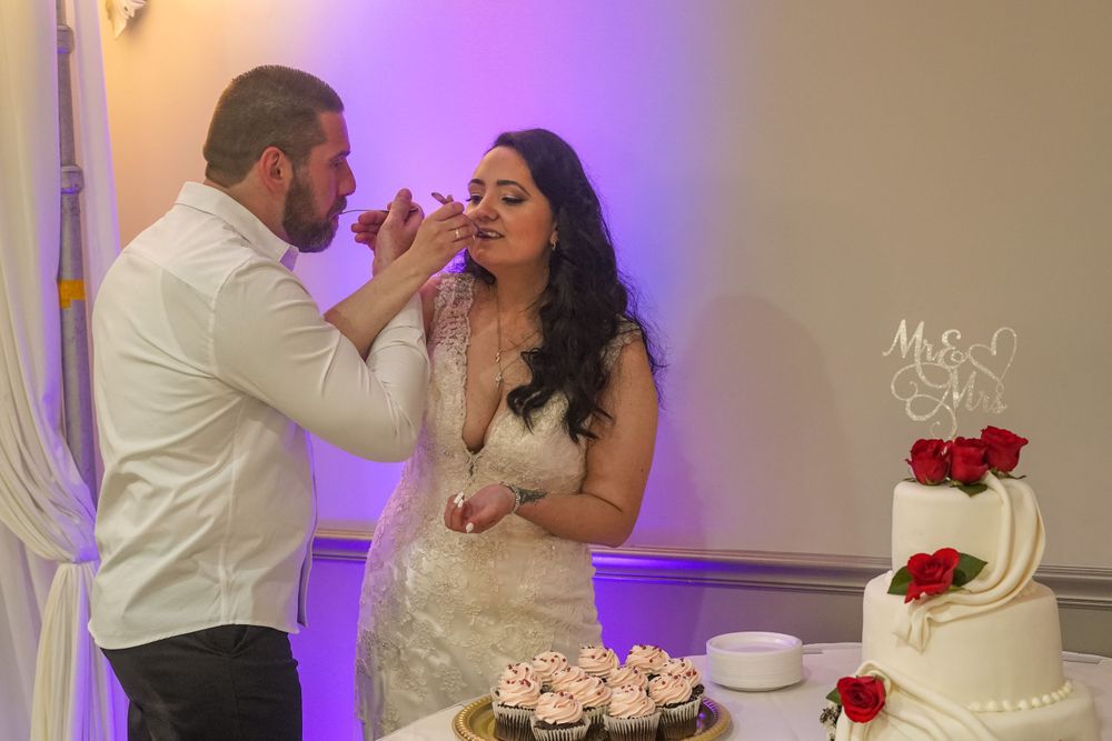 Newlyweds share playful moments while cutting and eating their wedding cake together.