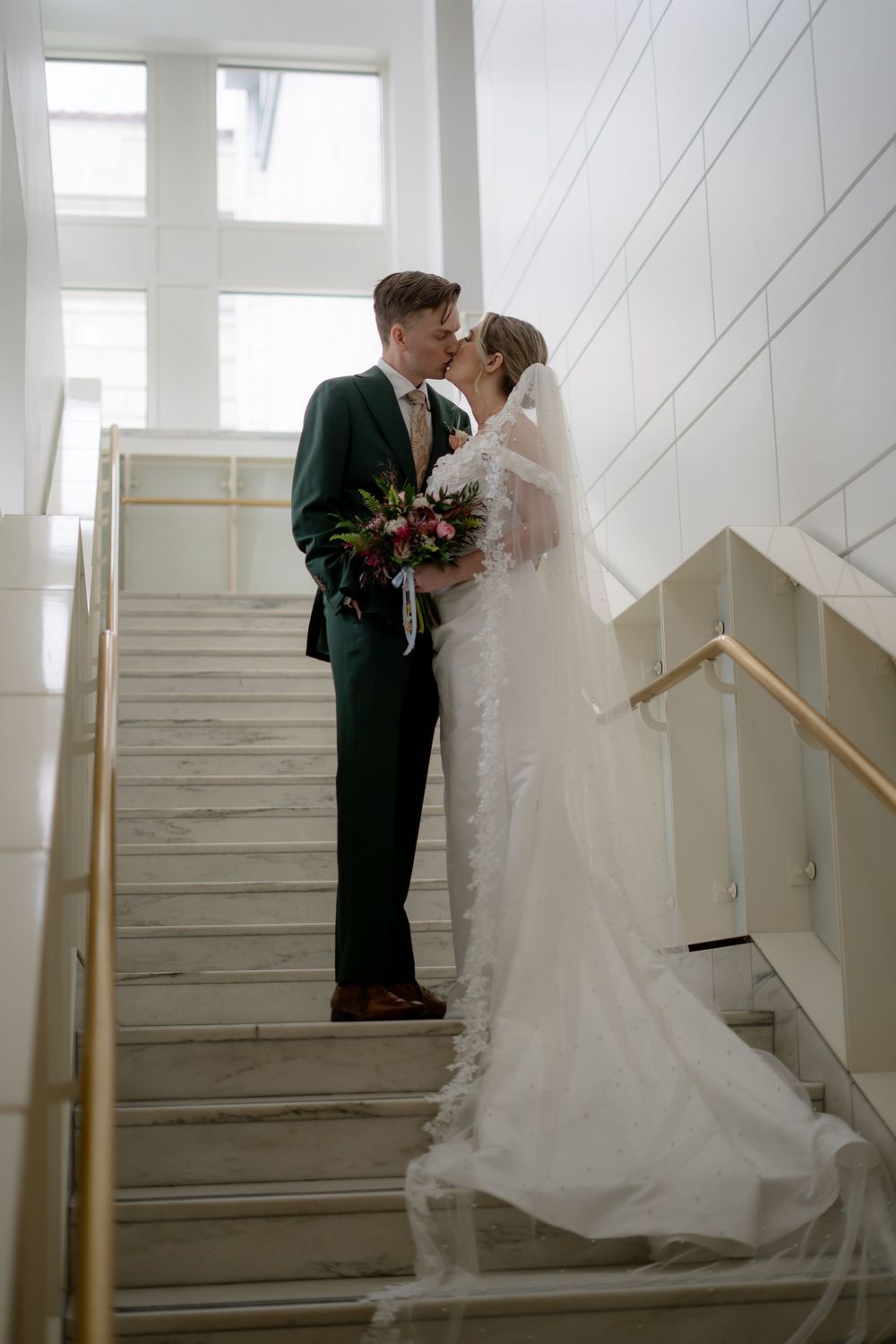 Wedding couple sharing intimate moments on marble staircase.