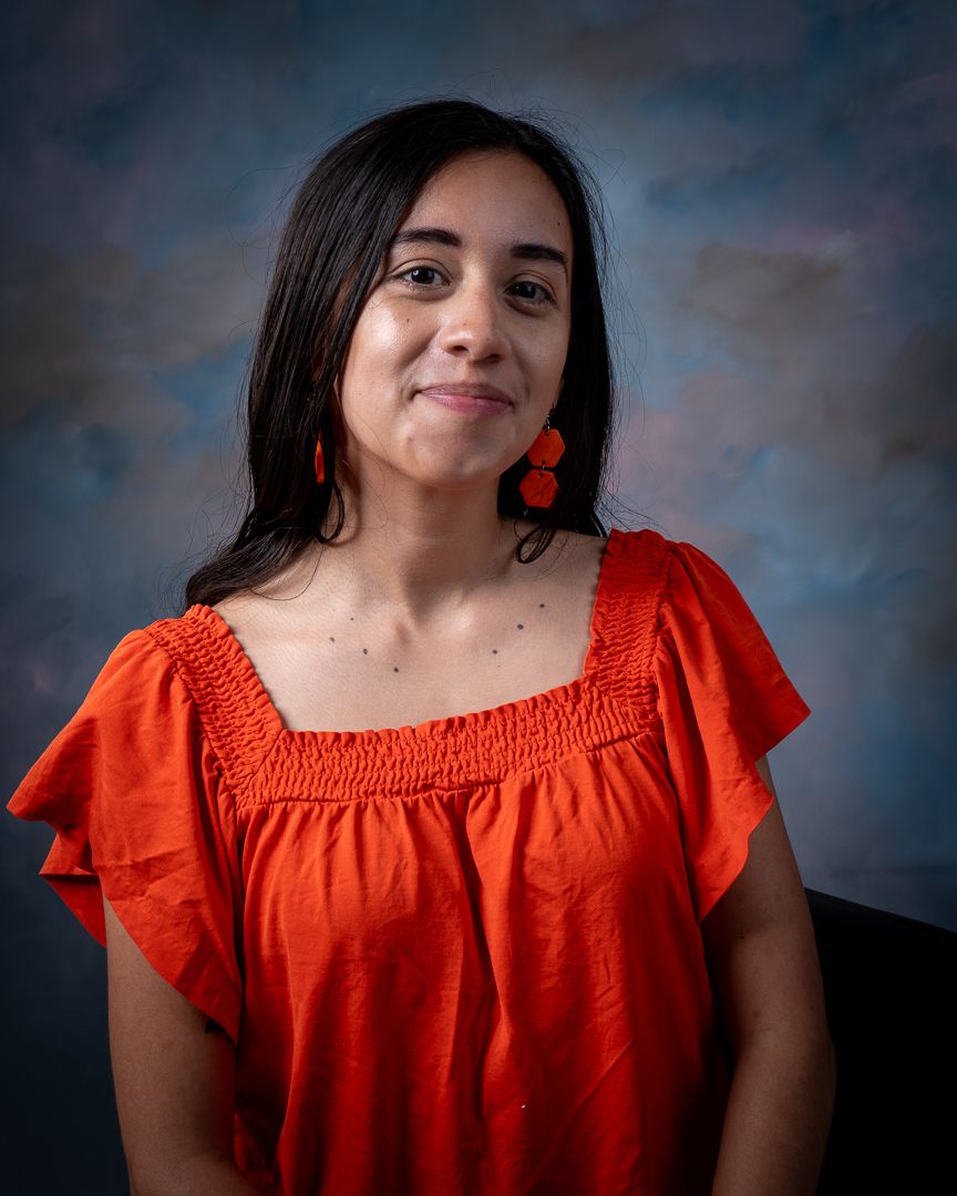 Portrait of a person in red top with matching earrings against studio background.