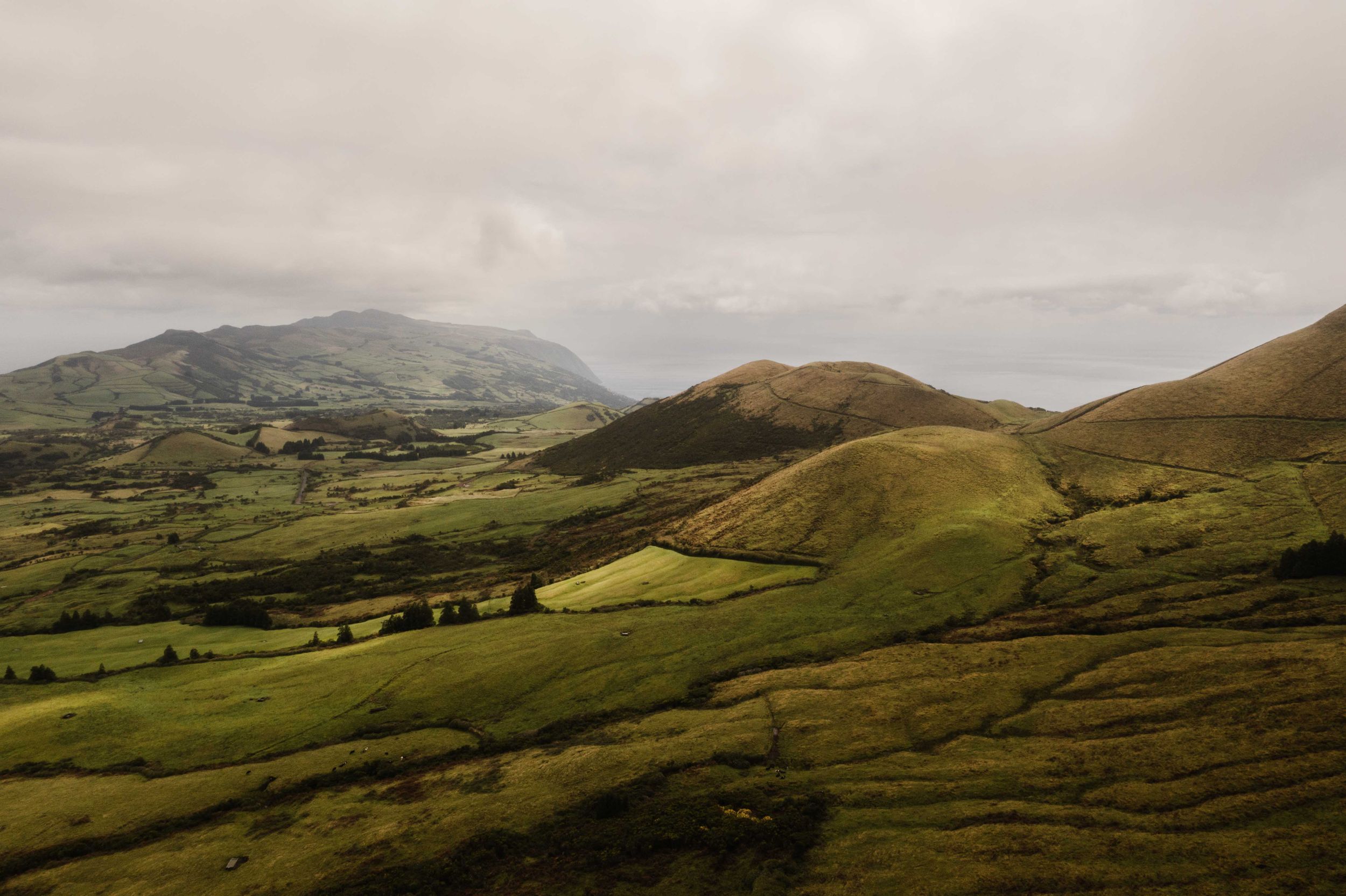 Rolling green hills and valleys stretching toward distant misty mountains.