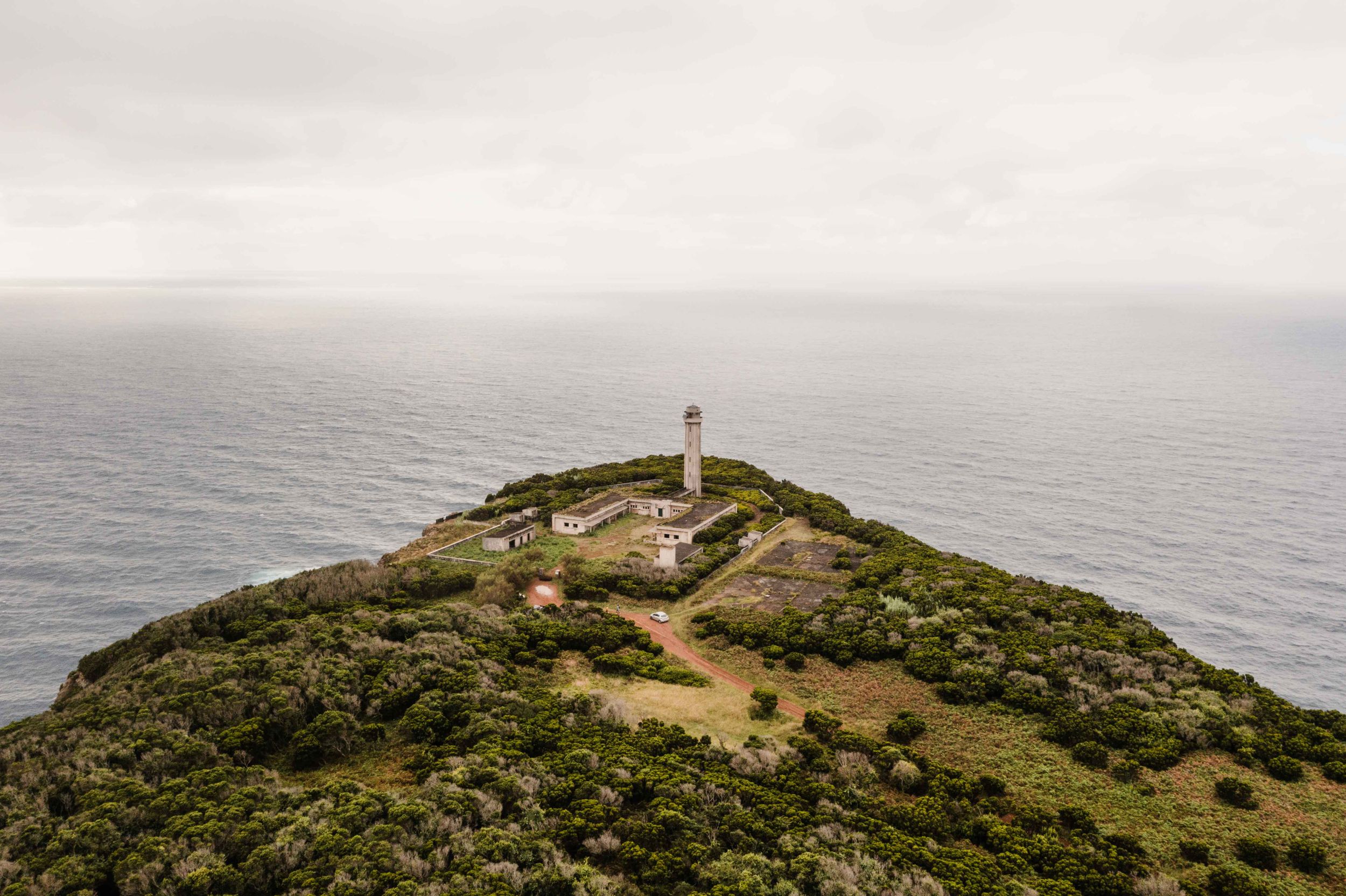 Lighthouse perched on a windswept hilltop overlooking the vast ocean.