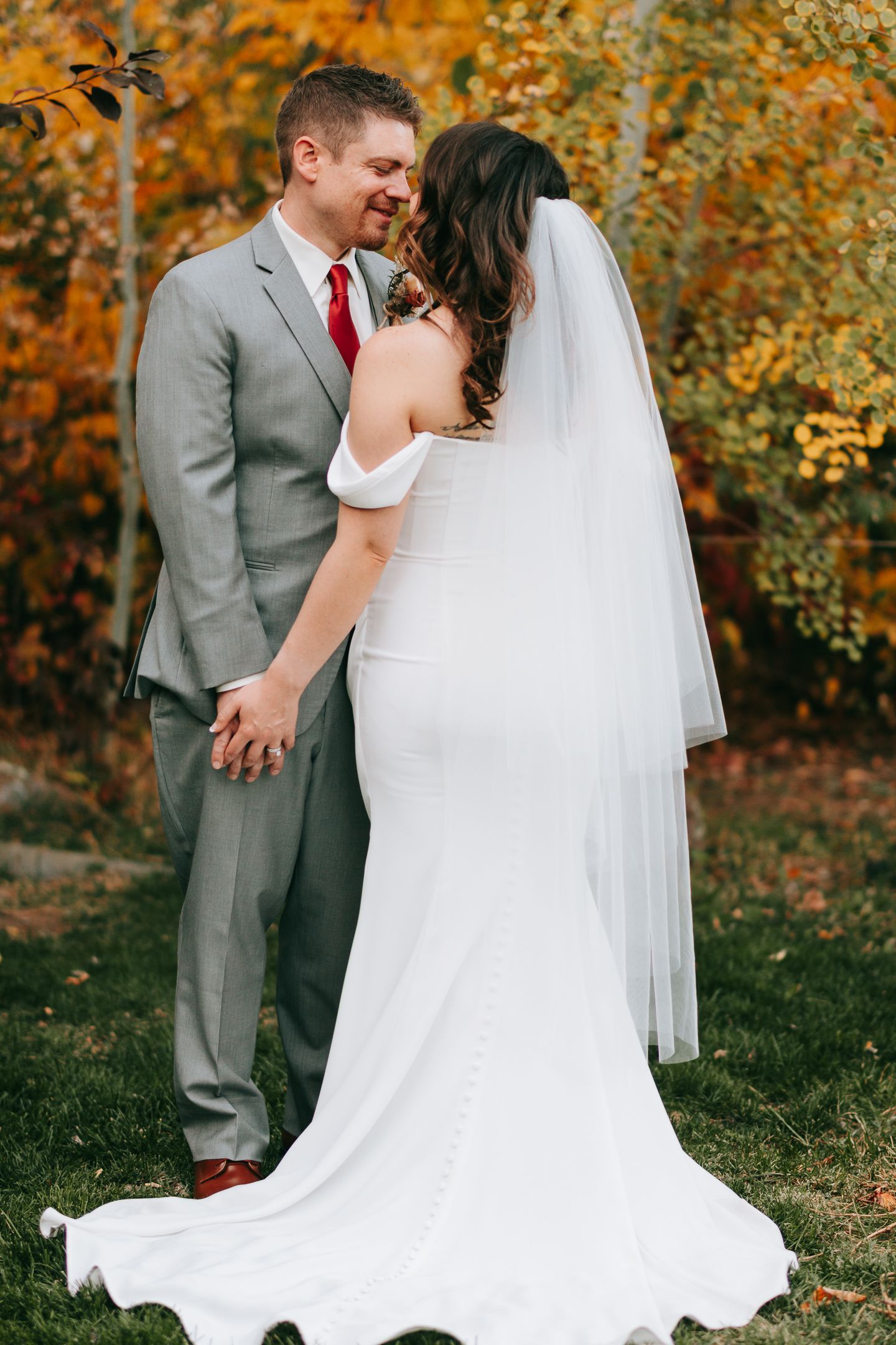 Wedding couple sharing joyful moment against vibrant fall foliage.