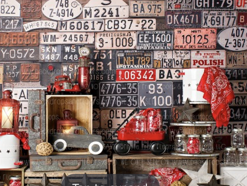 Vintage license plates from various states cover a wall above a rustic shelf displaying red lanterns and antique collectibles.