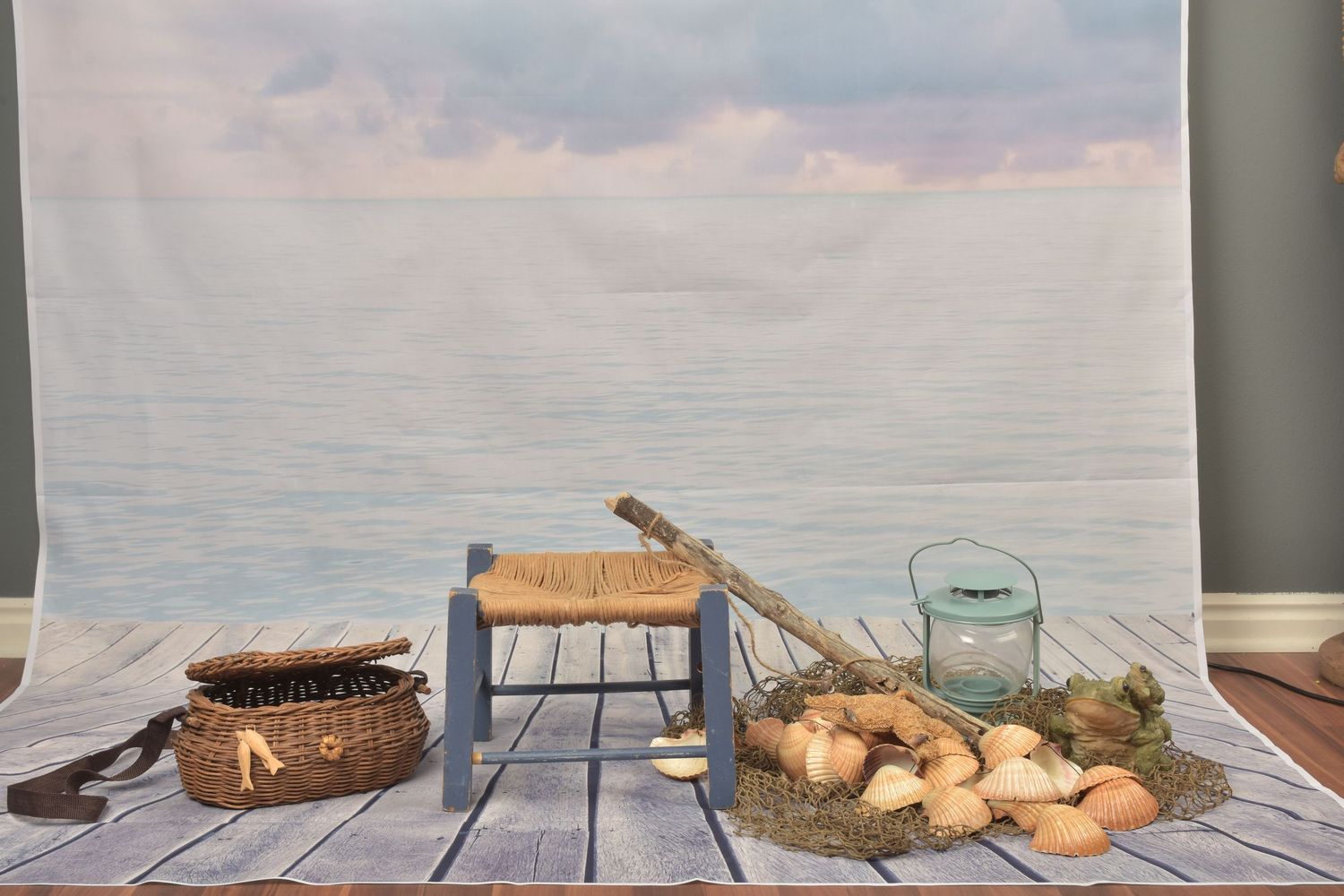 Nautical fishing scene with wicker basket, wooden stool, lantern, and eggs on netting against ocean backdrop.