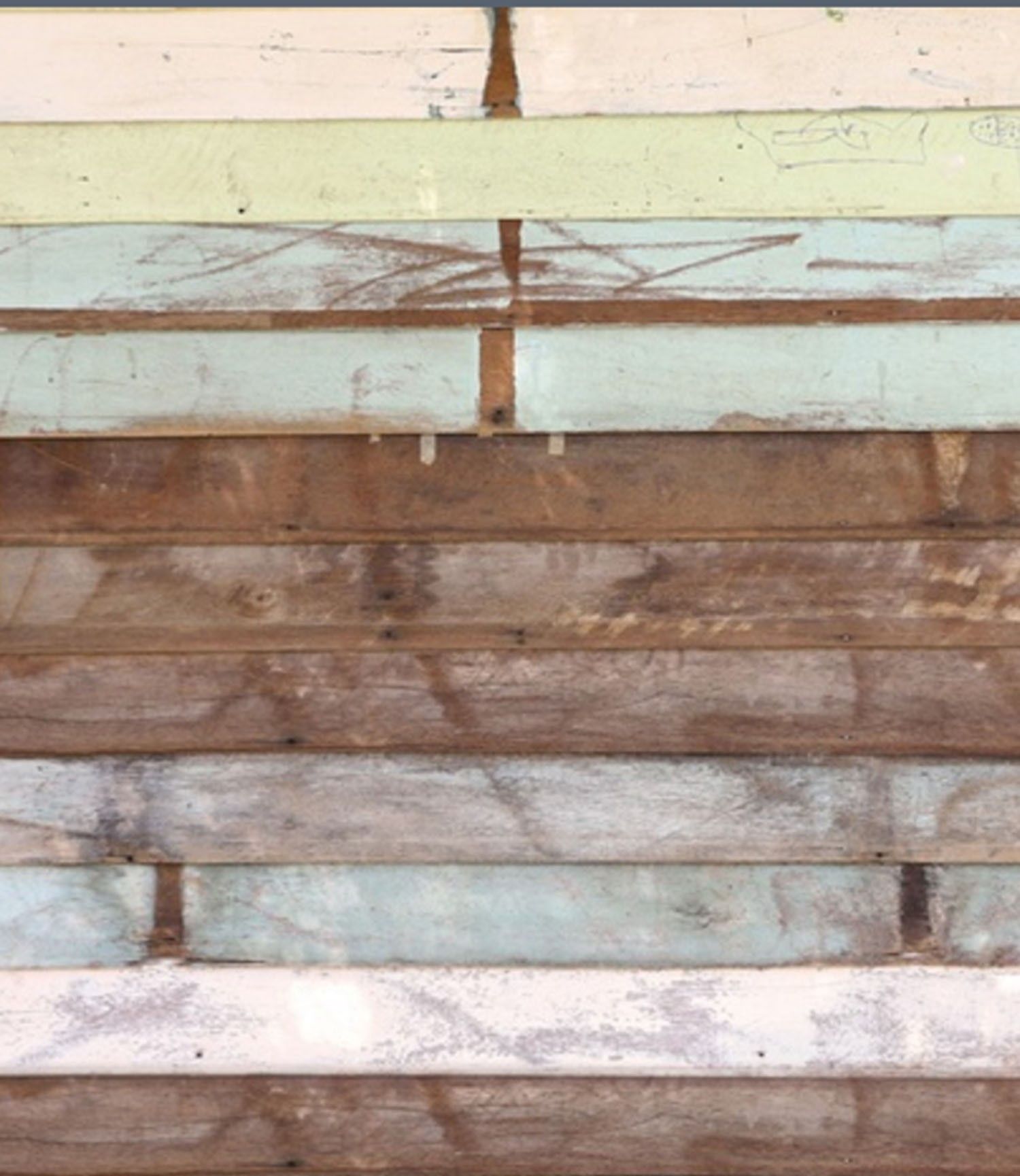 Rustic reclaimed wood planks with weathered paint in muted tones of green, blue, and brown for a vintage backdrop.