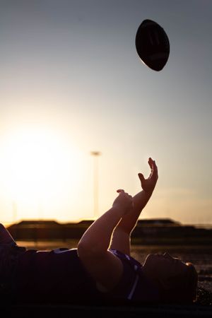 On the football field throwing a football.