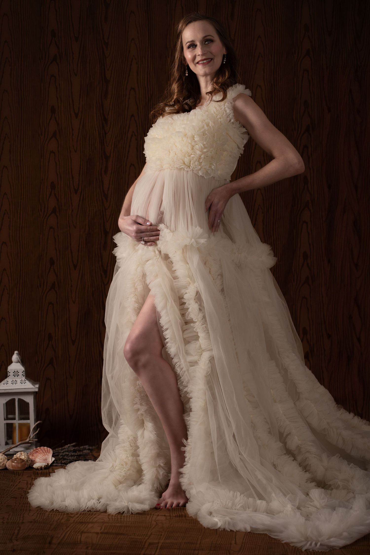 Elegant maternity portrait in flowing cream gown with ruffle details and dramatic train.