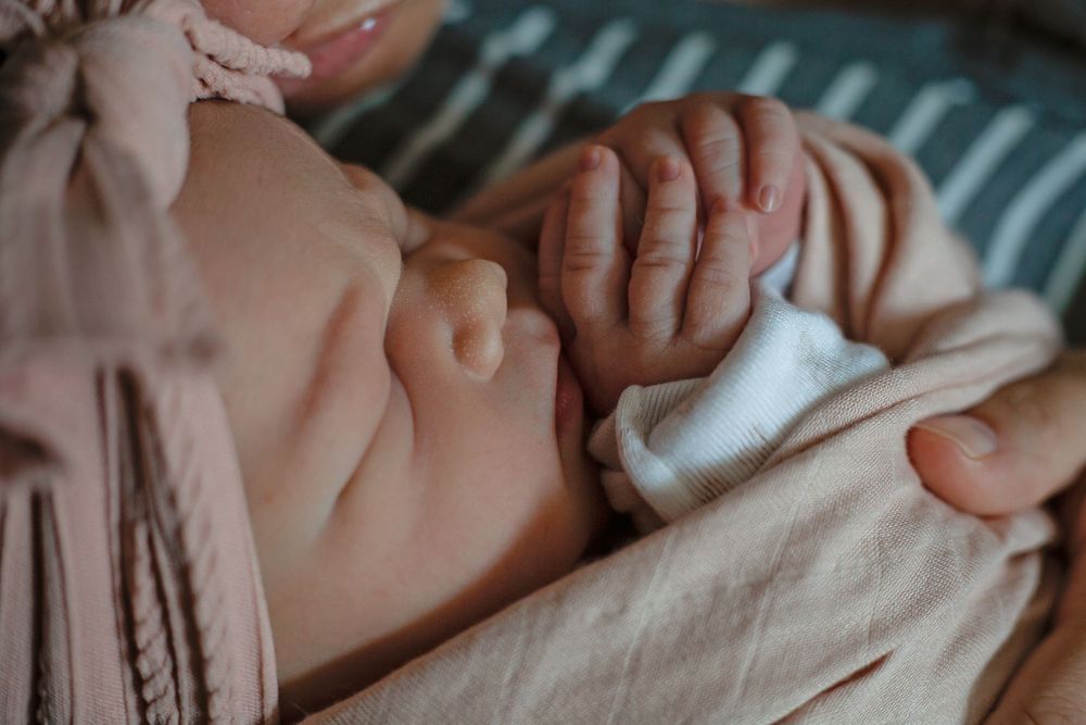 Newborn baby sleeping peacefully wrapped in soft pink blanket.