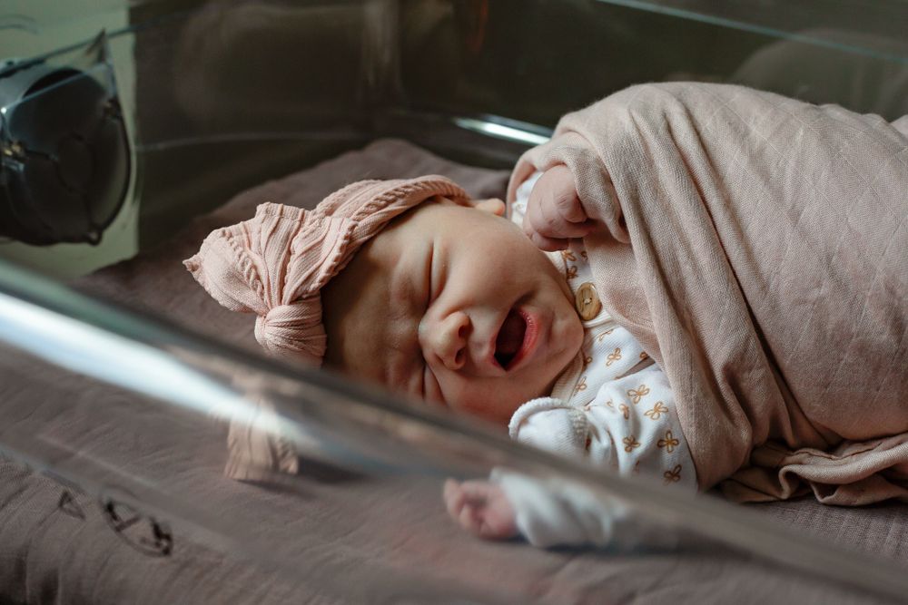 Baby wrapped in pink blanket smiling while sleeping.