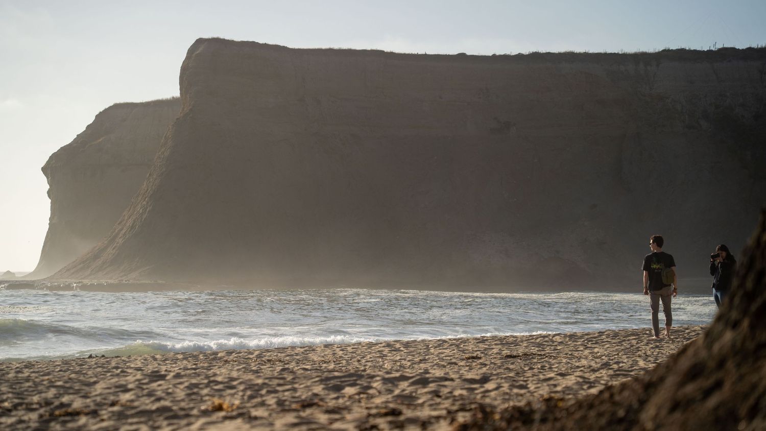 Dramatic coastal cliffs and beach landscape during golden hour.