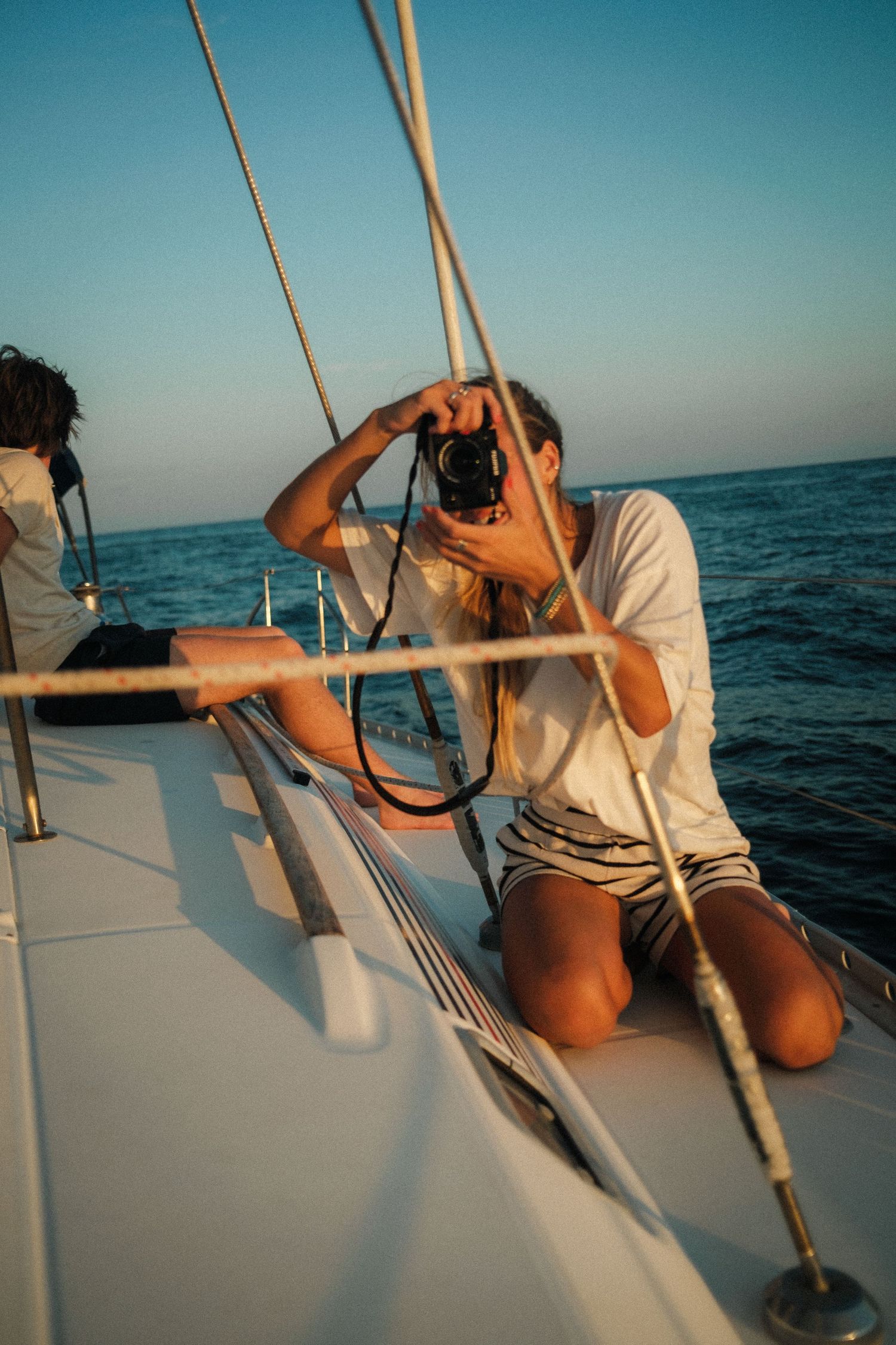Person relaxing on a sailboat deck against blue ocean waters and sky during a peaceful day at sea.