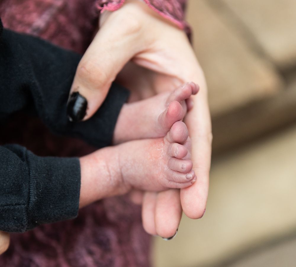 Close-up shot of baby's tiny foot being held in adult hands.