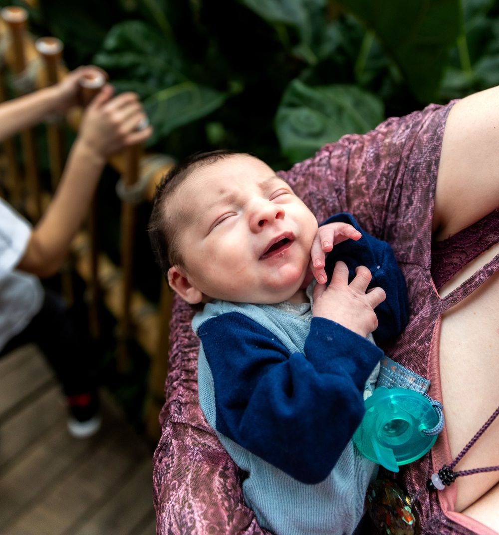 Smiling infant in navy blue outfit resting against floral print fabric.