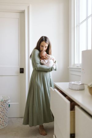 Heartwarming photo of mom holding her newborn close to her chest, captured indoors in beautiful natural light