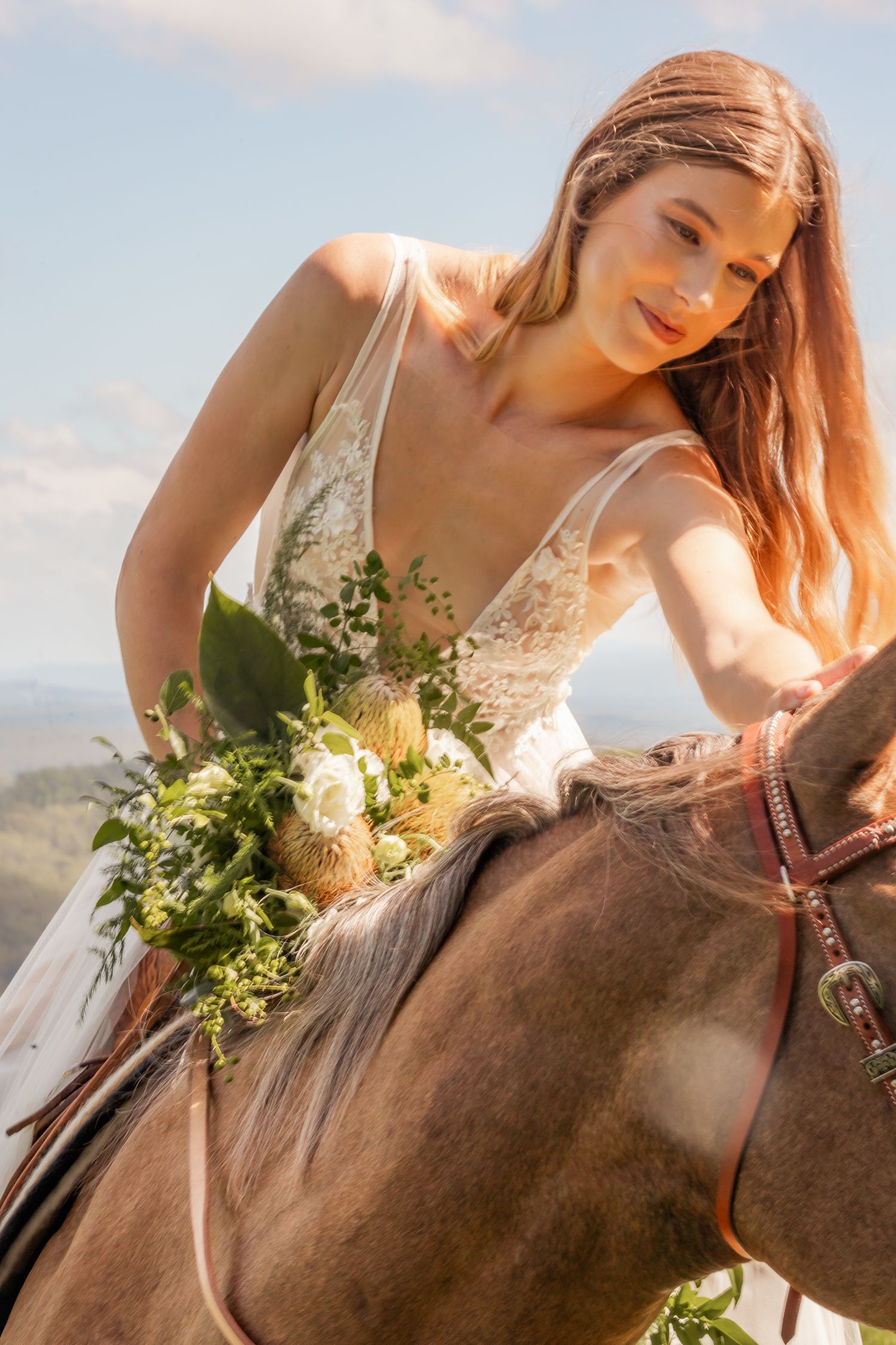 Close-up of a bride holding a bouquet while riding horseback under sunny skies. Maleny Sunshine Coast.