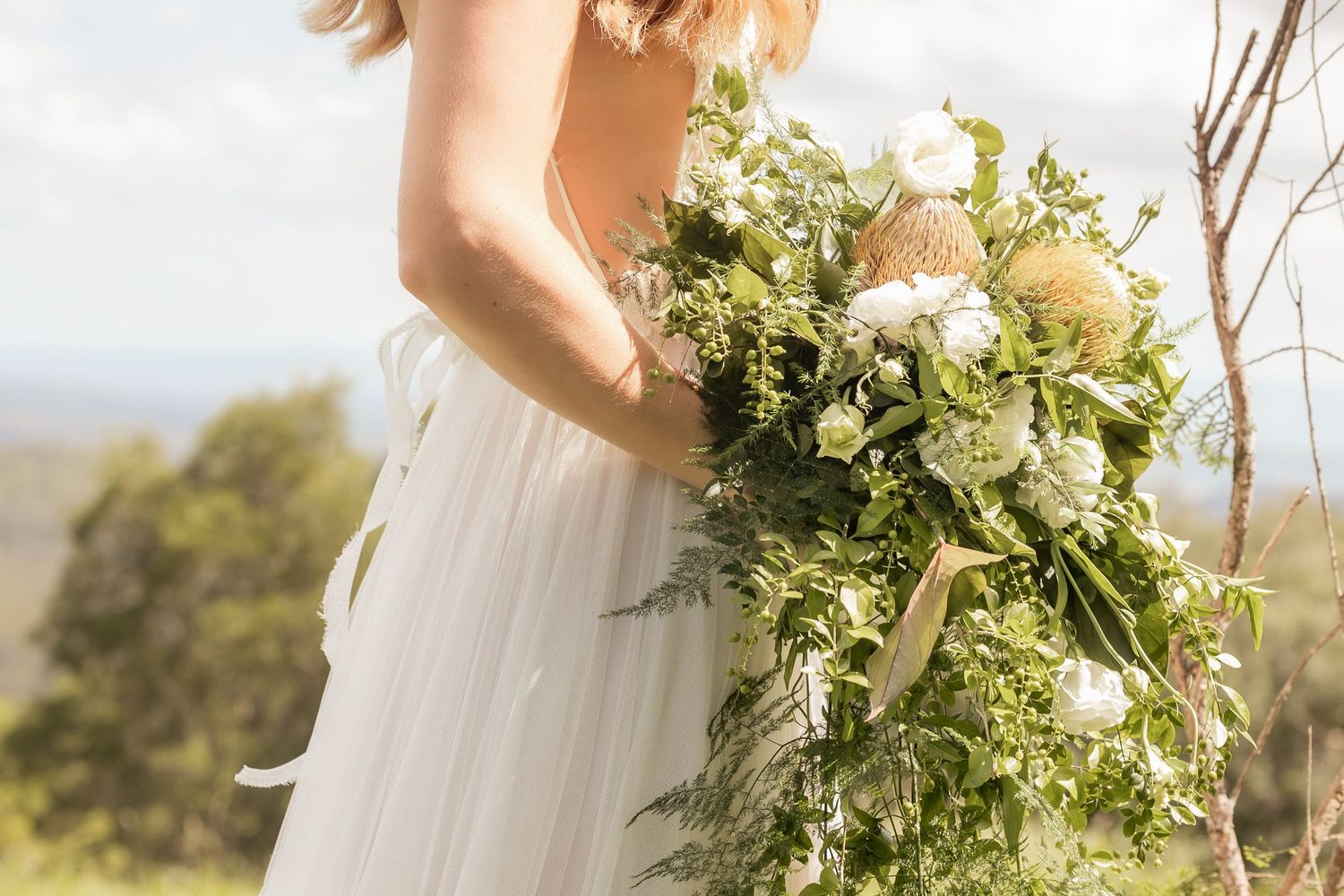 Fresh greenery and floral arrangements adorn an outdoor wedding celebration in natural sunlight. Maleny Sunshine Coast.