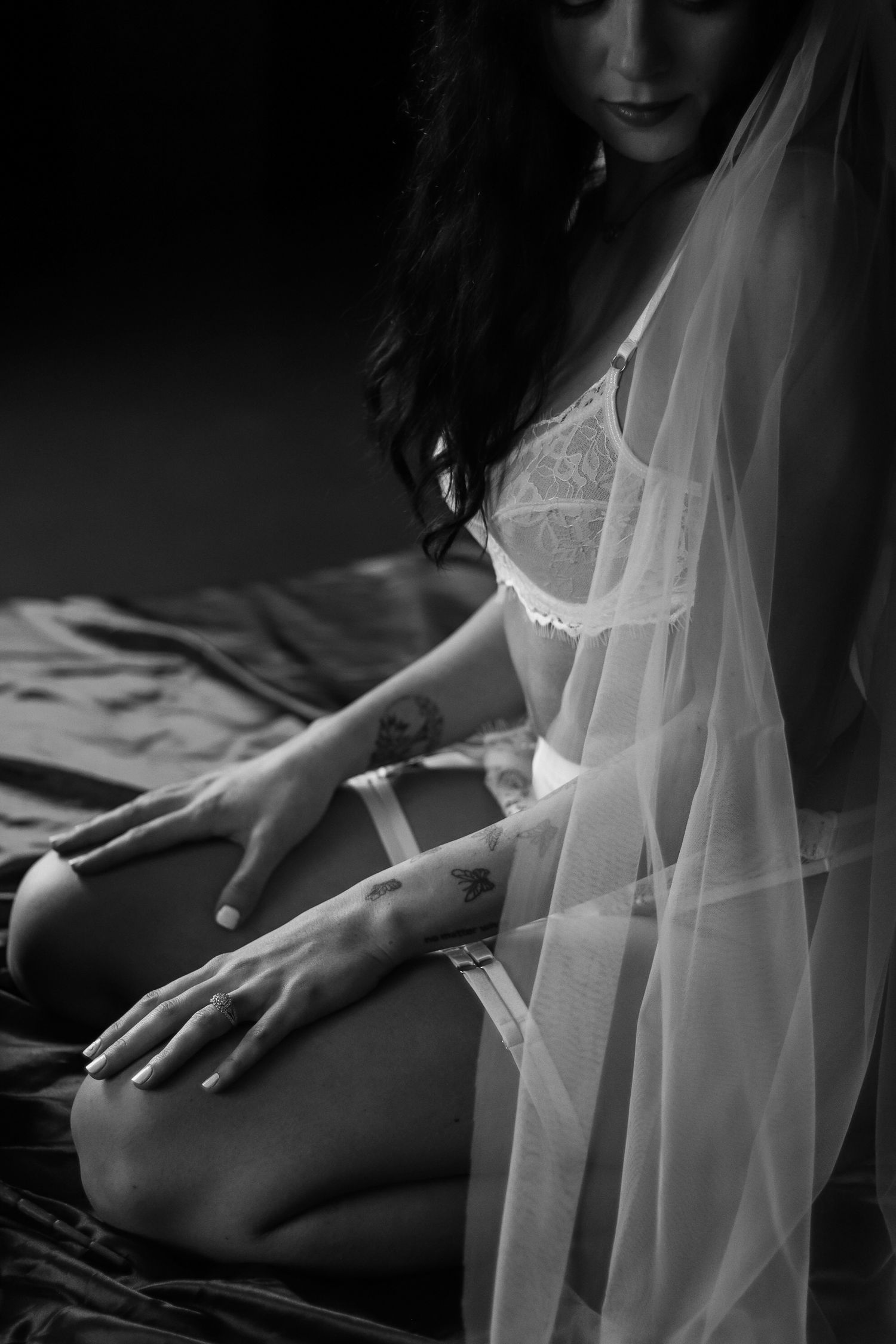 Intimate black and white portrait of woman in white lace lingerie and veil.