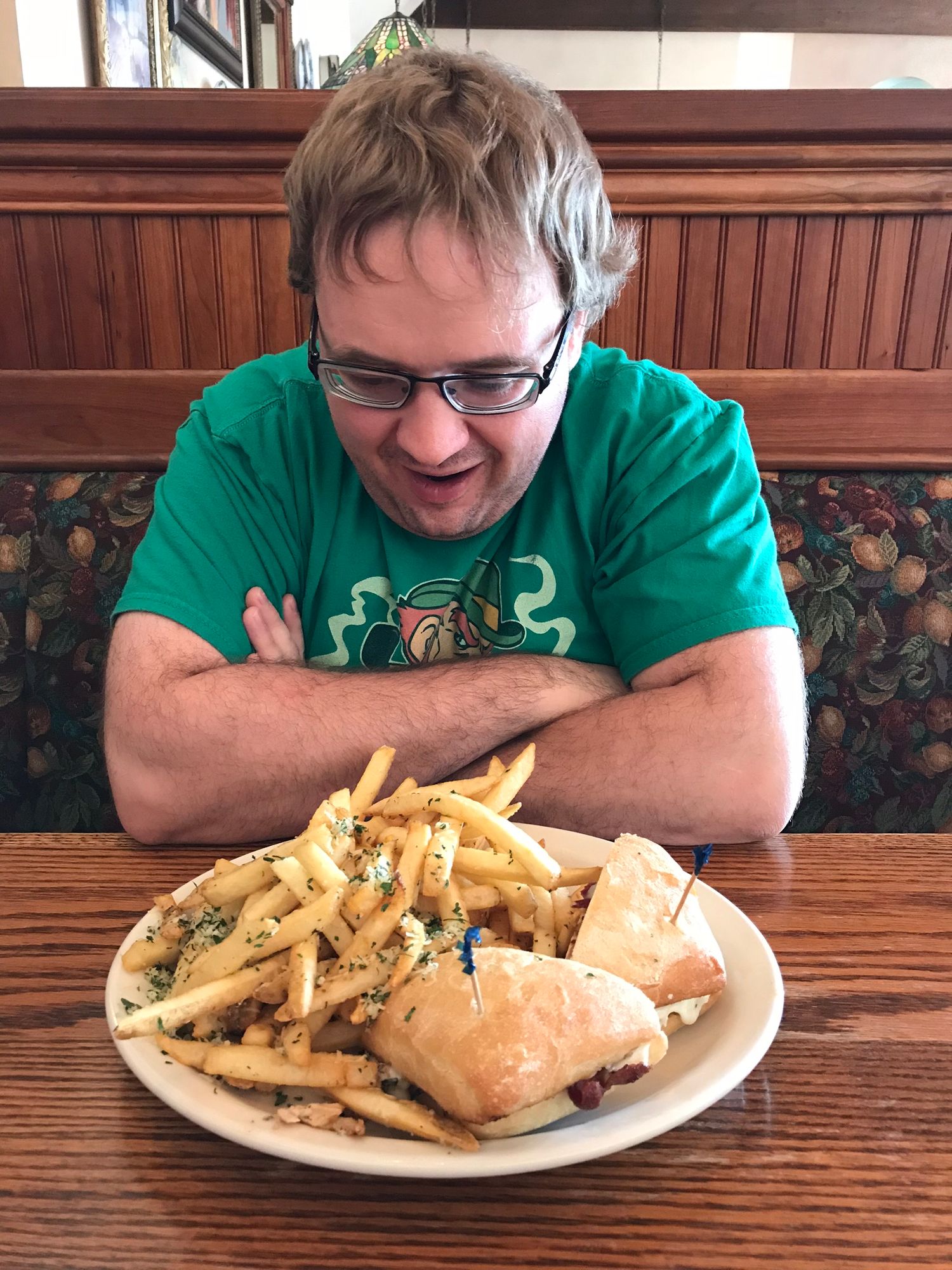 Plate of french fries and sandwich served at a restaurant booth.