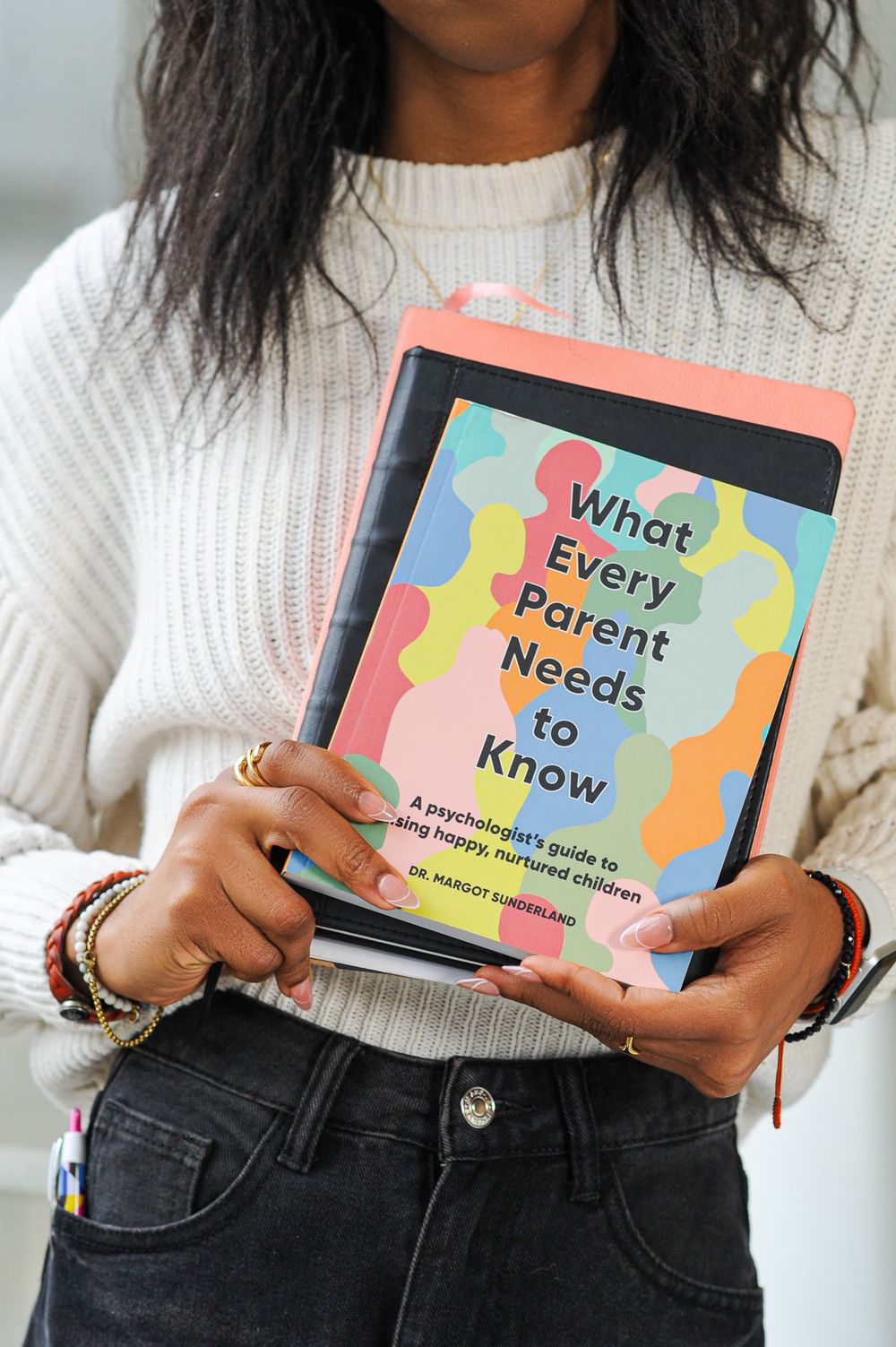 Hands holding a colorful parenting guide book titled 'What Every Parent Needs to Know'.