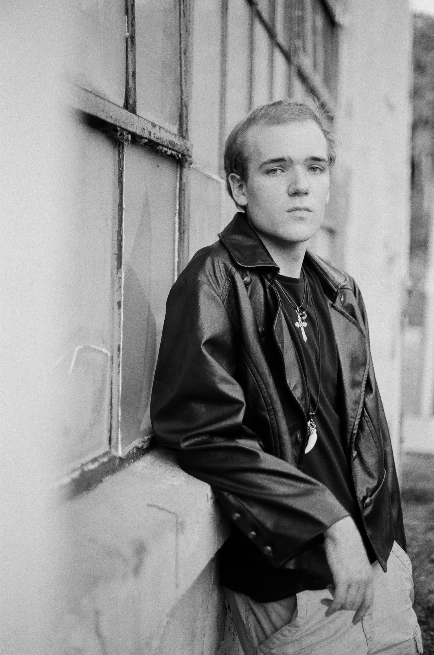 Black and white portrait series showing someone in a leather jacket against a light colored wall.
