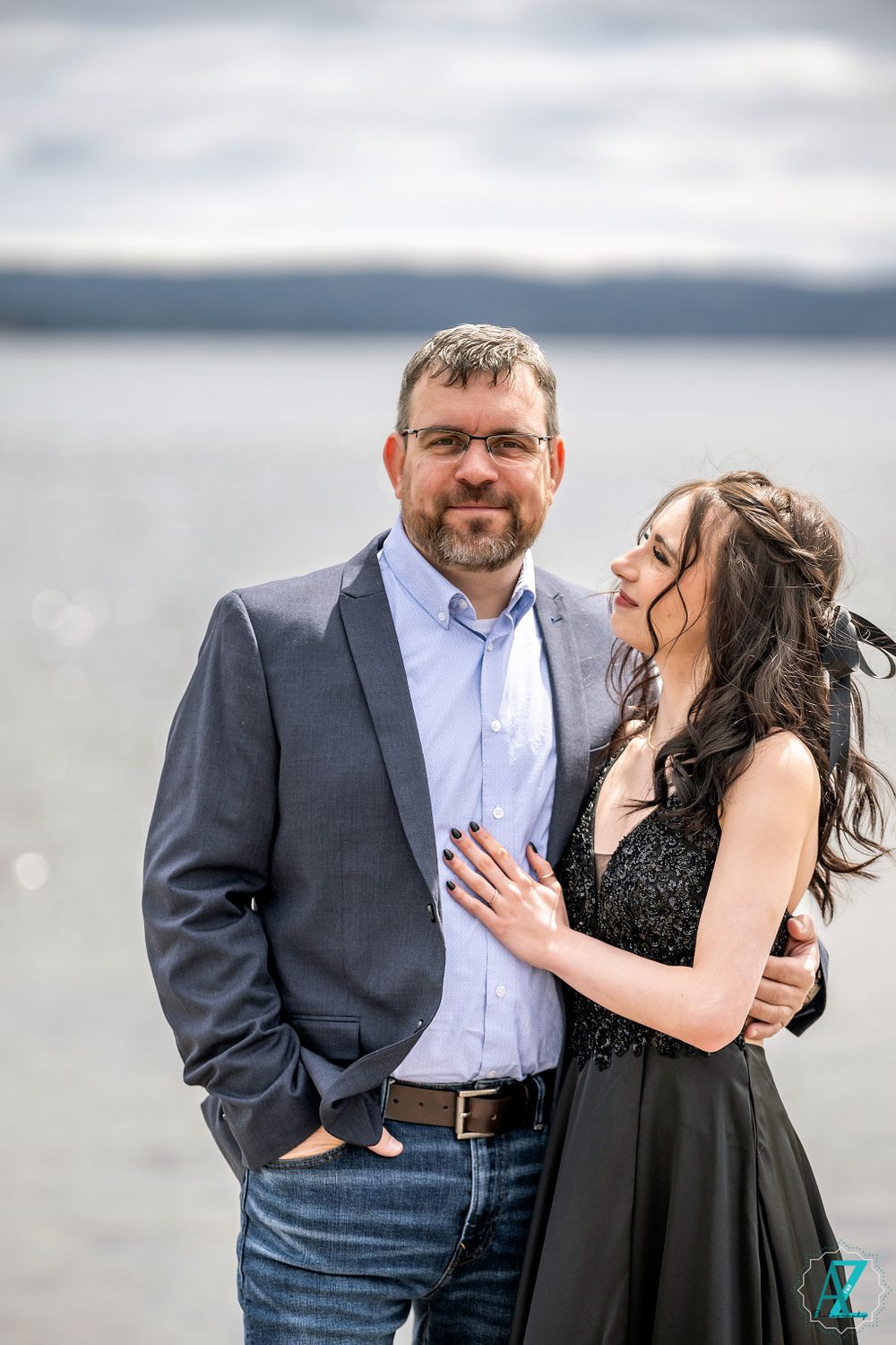 A sweet couple's portrait with a cloudy lake backdrop.