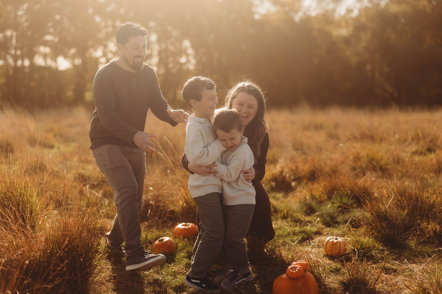 Family walking together through a golden field at sunset.