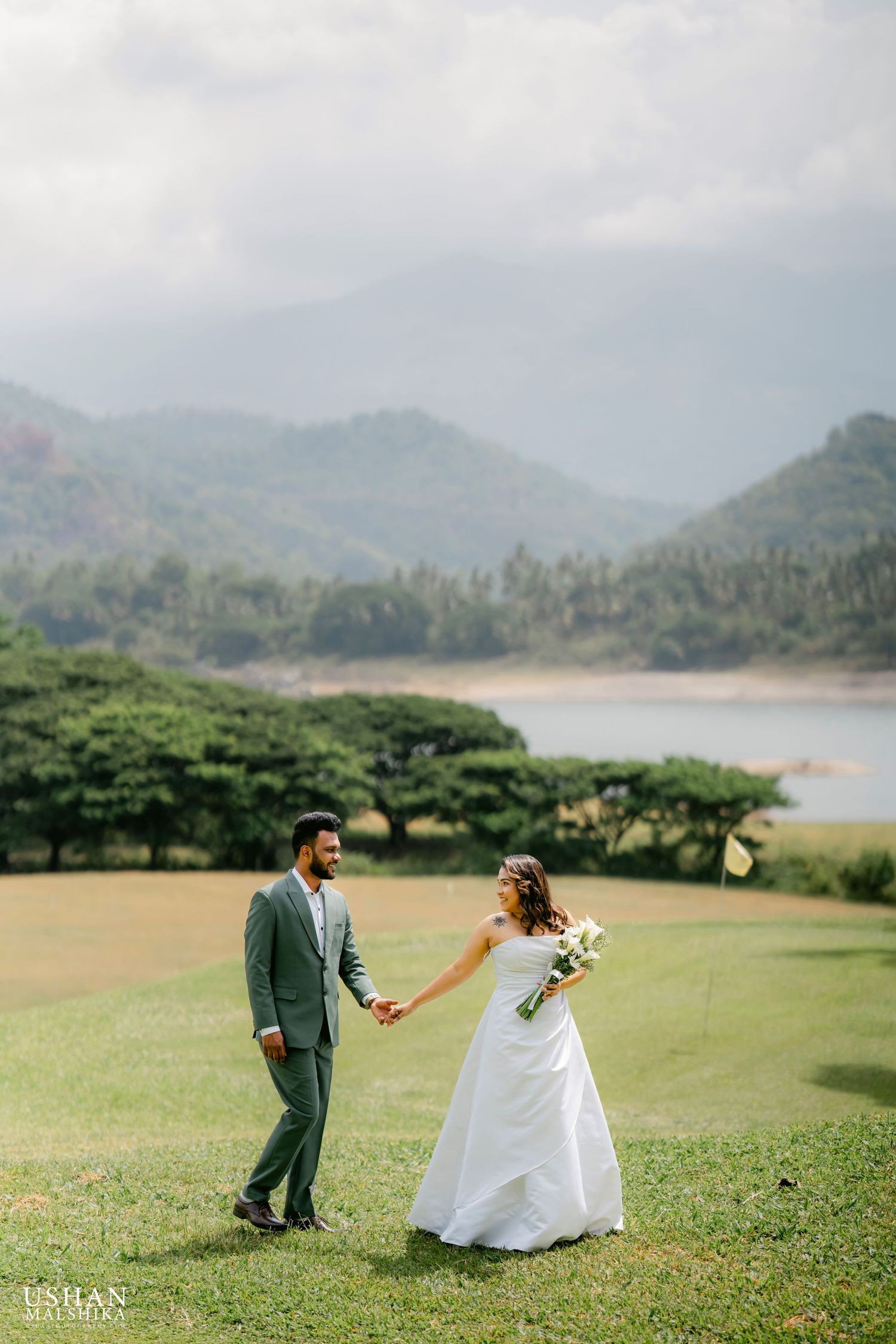 Wedding couple holding hands in scenic mountain landscape setting.