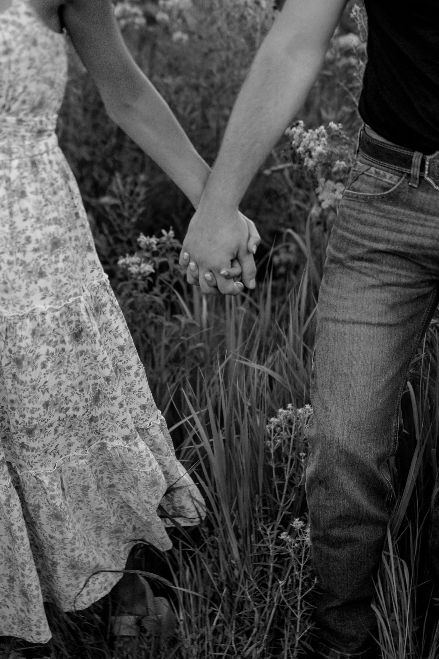 Couples photography session in a beautiful flower field, capturing intimate moments of clients holding hands.