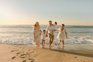 A joyful family running along the shore at Cronulla Beach during sunrise.
