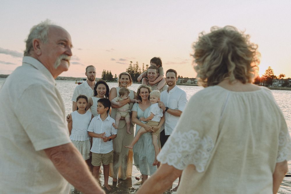 Group gathered on beach at sunset for casual outdoor celebration.