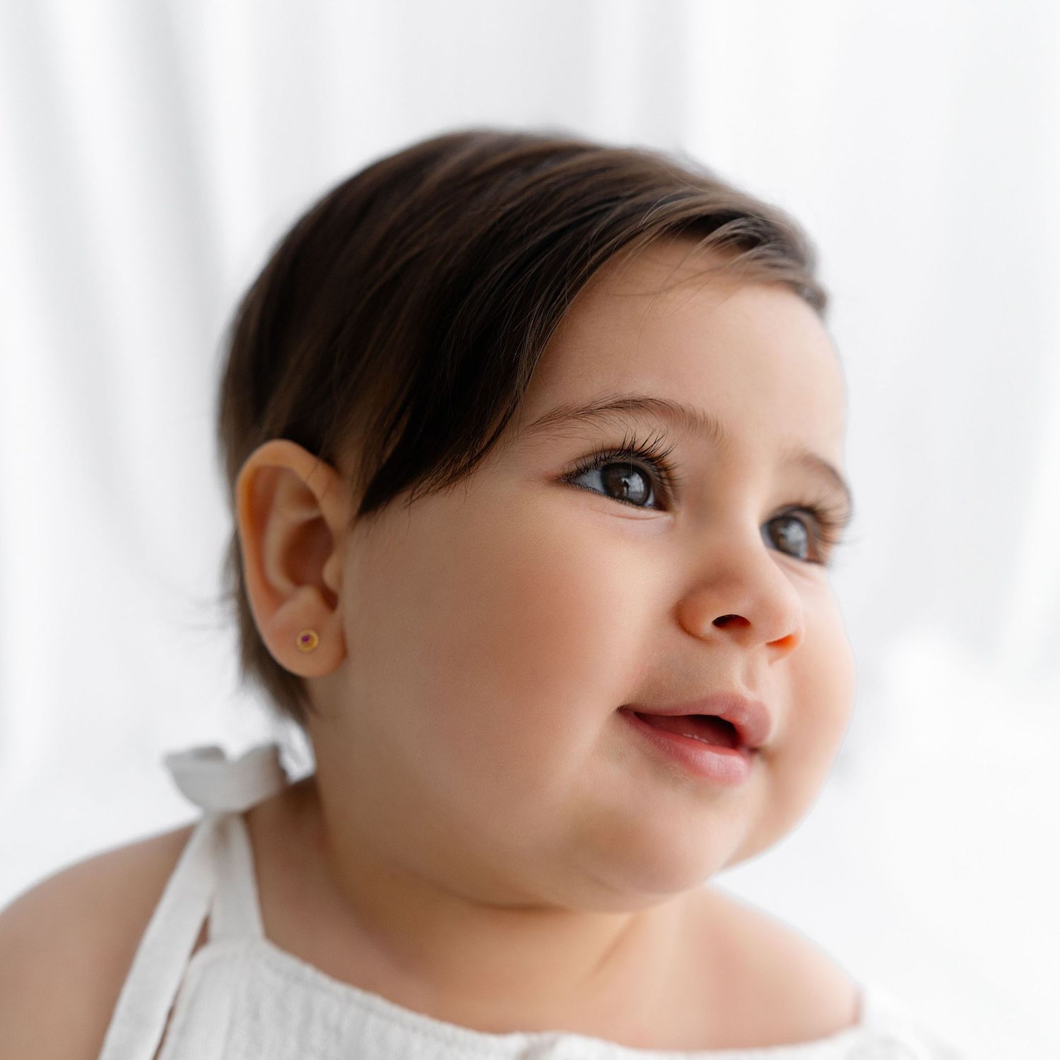 Close up portrait of baby in white against soft white background.