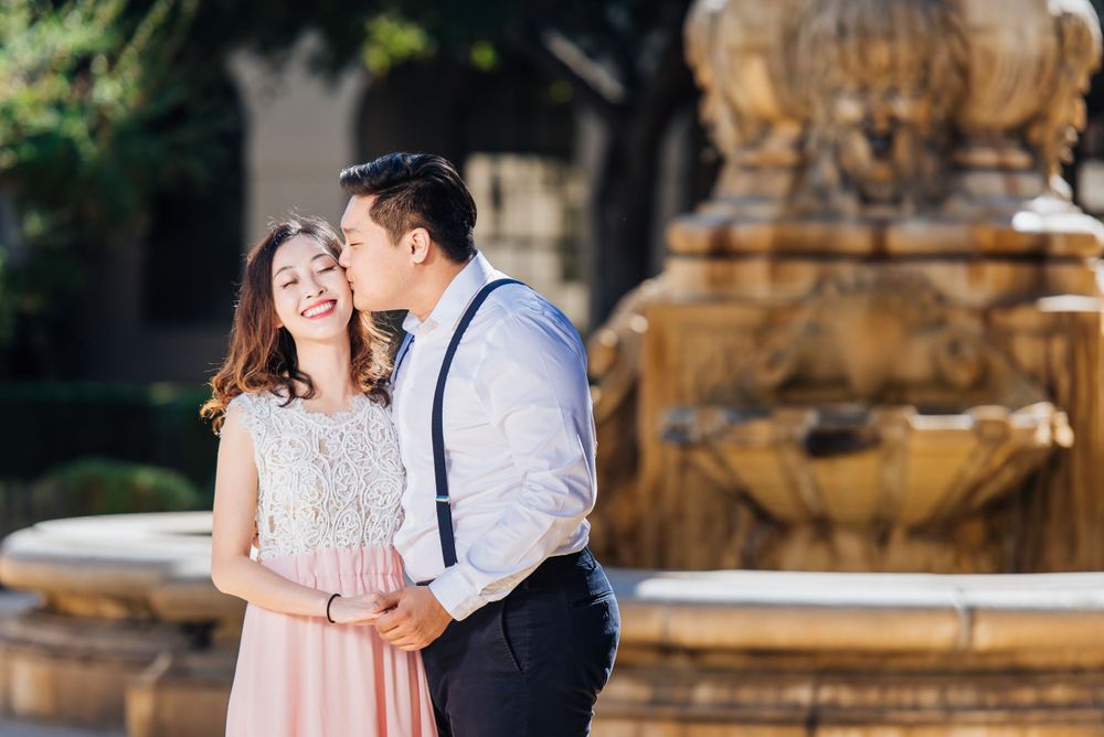 A romantic moment shared by a couple near an ornate fountain.