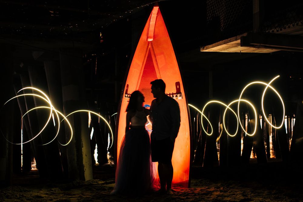 Silhouettes against an orange kayak with swirling light trails in the background.