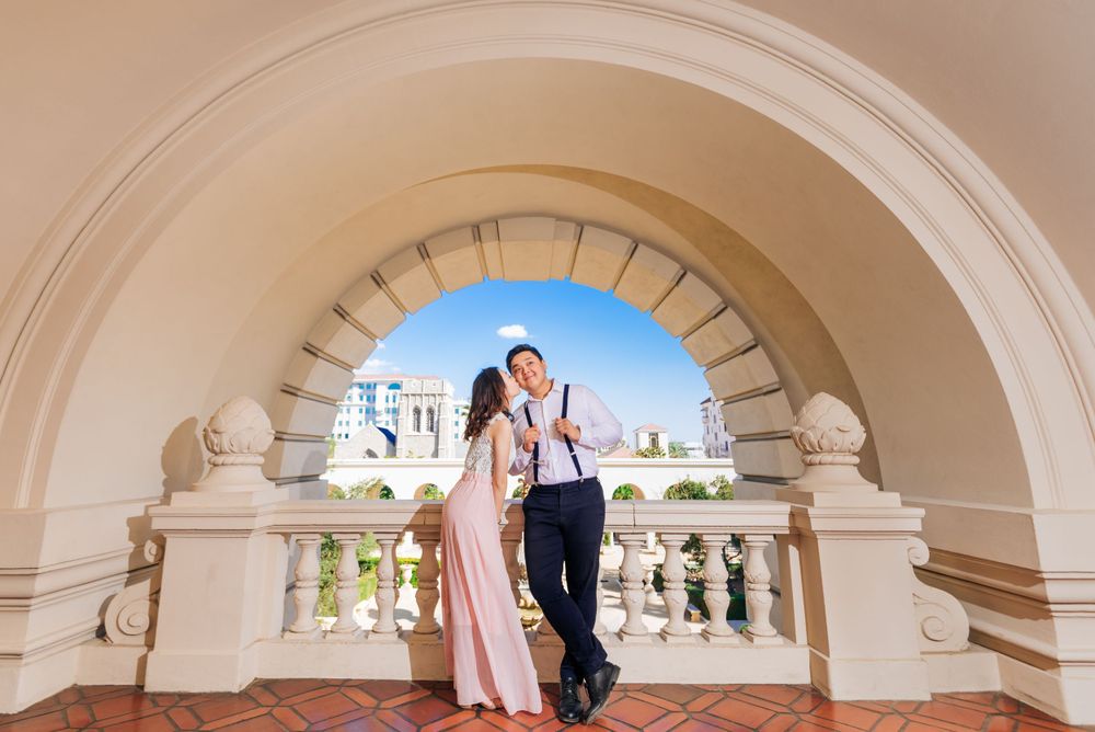 A couple posing under a classic arched passageway with ornate architecture.
