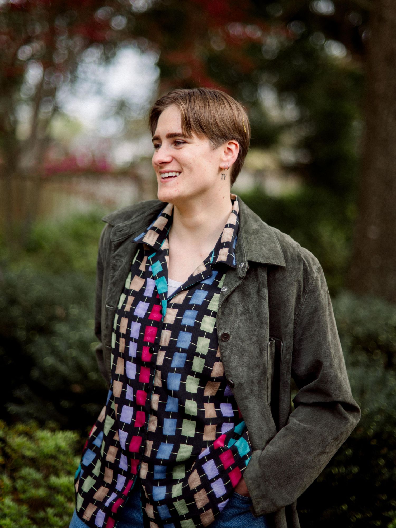 A colorful geometric patterned shirt paired with a dark jacket creates a casual outdoor look.