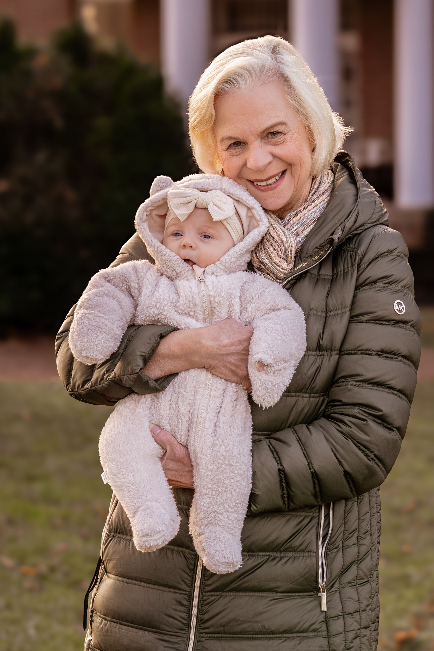 A person in a puffy winter coat holds and plays with a small white fluffy dog outdoors.