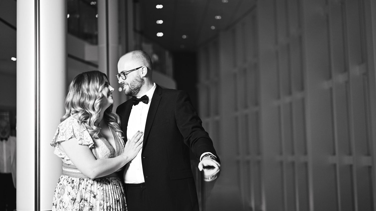 Romantic black and white portrait of couple sharing intimate moment in formal attire.