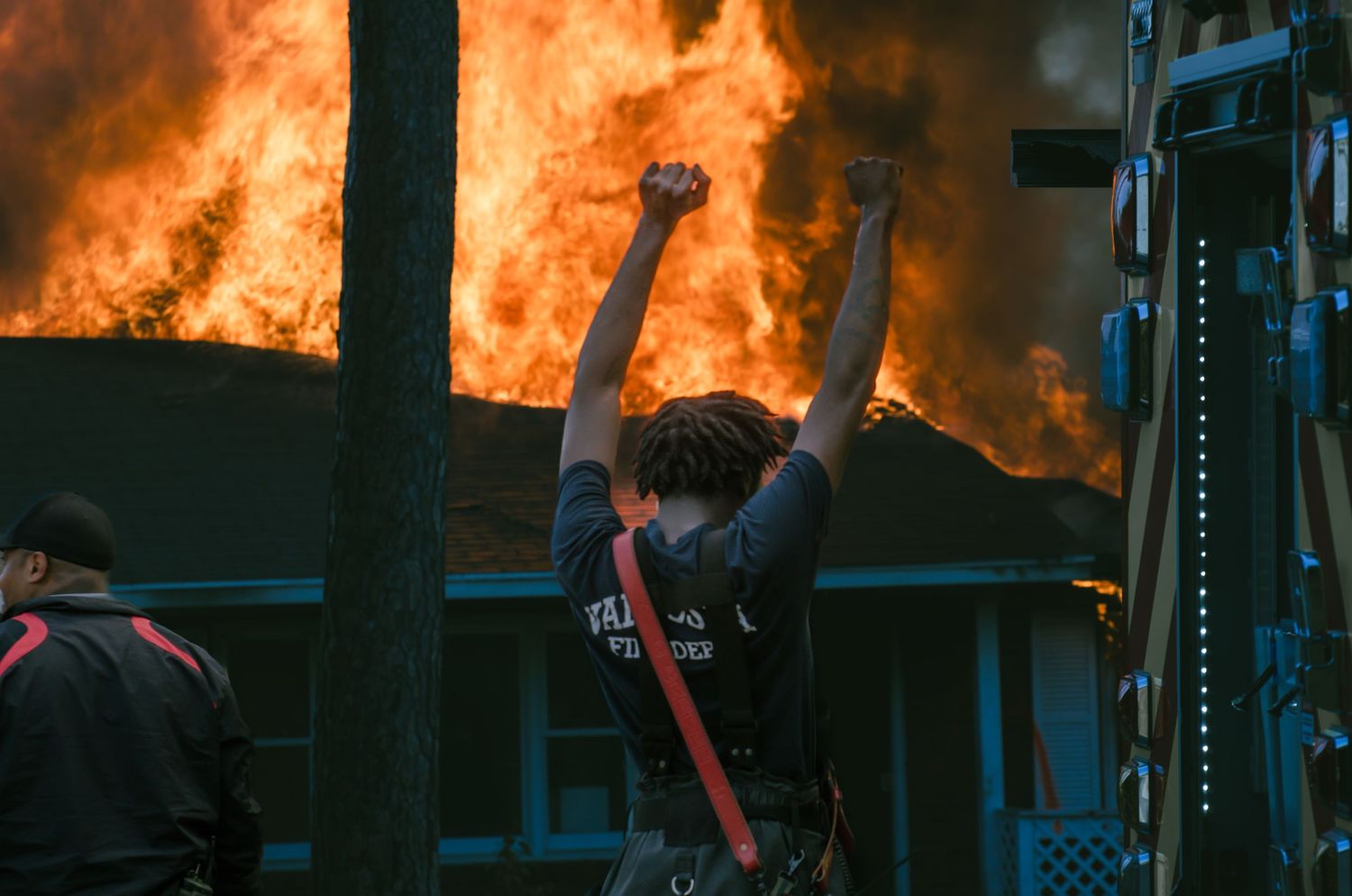 Firefighter in protective gear performing training exercise outdoors under blue sky.