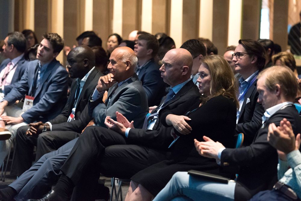 Business professionals attentively seated in audience at corporate conference event.